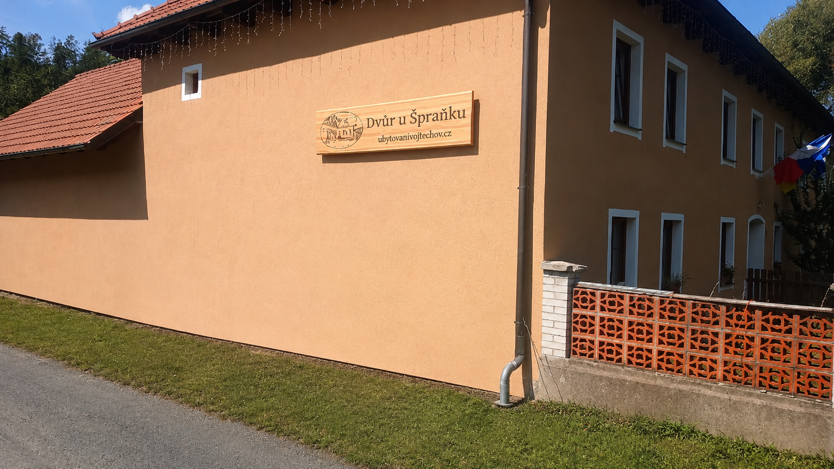 Velká modřínová cedule Dvůr u Špraňku na fasádě ubytování ve Vojtěchově