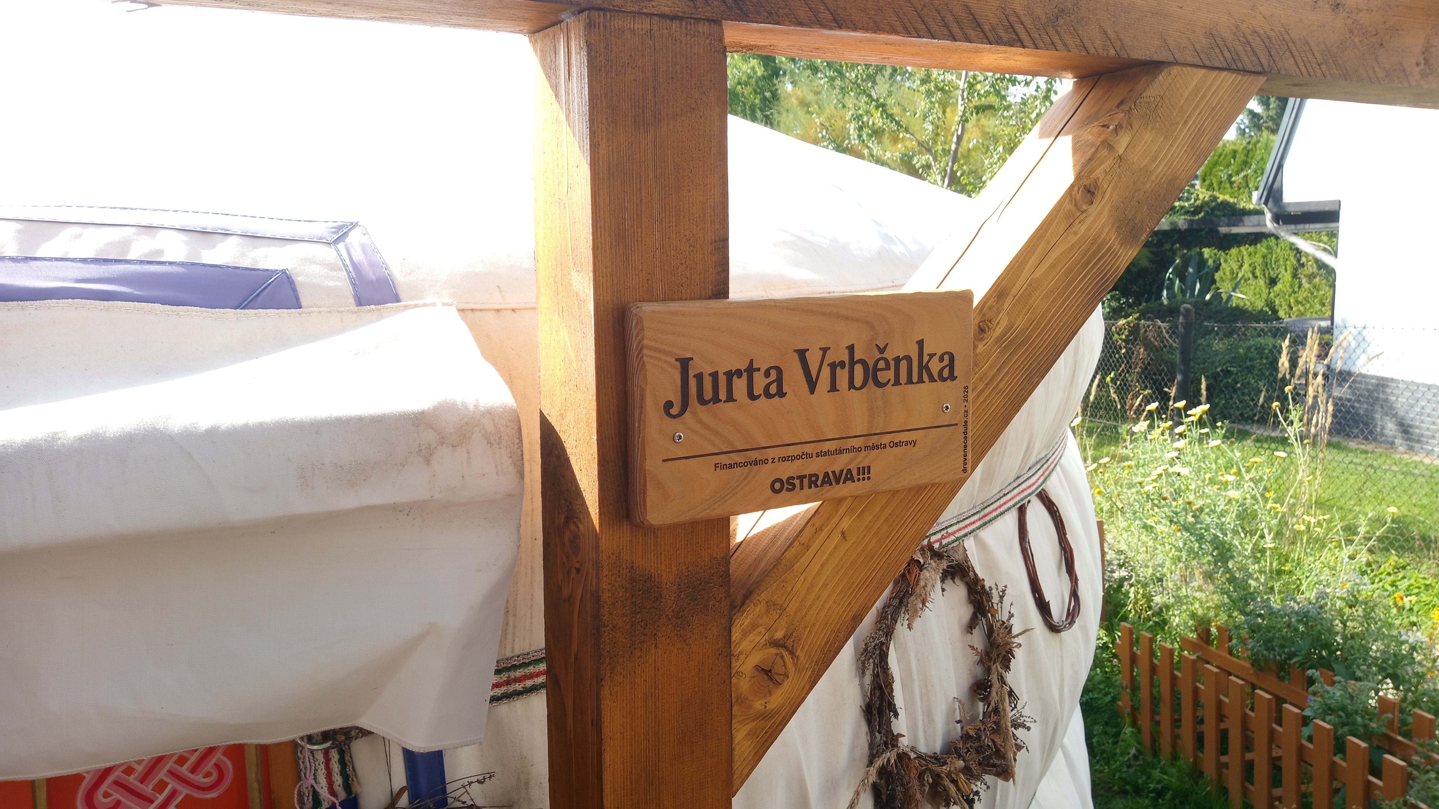 Cedulka Jurta Vrběnka uchycená na dřevěné konstrukci u jurty